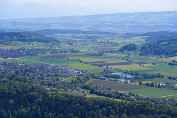 Fototapeta premium Aerial view of midland with agricultural fields, wood, ponds and hills seen from local mountain Uetliberg on a sunny spring day. Photo taken May 18th, 2022, Zurich, Switzerland.