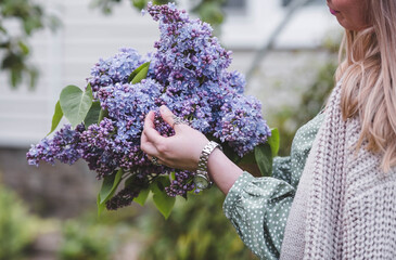 Hands of a woman in close-up with a bouquet of lilacs. Authenticity. Environmental friendliness. Content for a floral store. Sale of flowers.
