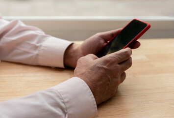 close-up of older male hands typing a message on a cell phone