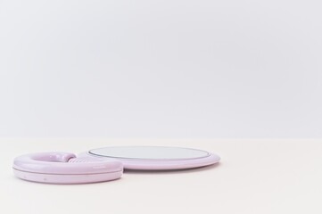round mirror with pink frame on a bright beige desk against soft gray wall