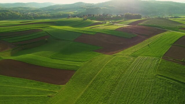 AERIAL: Gorgeous hilly rural countryside with small villages and farming land. Picturesque agricultural landscape with lovely pattern of pastures and farm fields. Idyllic landscape in afternoon light.