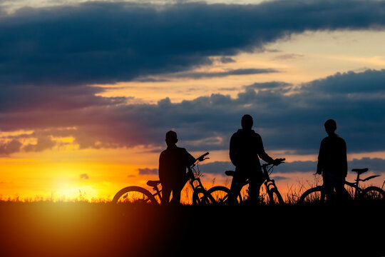 biker family. silhouette mather with two kids on bikes at sunset