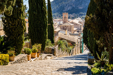 Carrer del Calvari staircase lined with cypress leads 365 steps downstairs to the old town of Pollensa with great view over rooftops to the church Santa Maria dels Àngels and mountain Puig de Maria. - obrazy, fototapety, plakaty