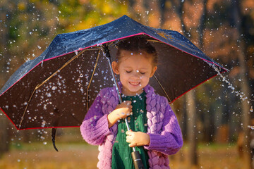 Girl with umbrella under mushroom rain in autumn park.