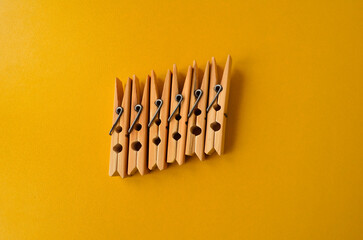 several wooden clothespins close to the center on a bright yellow background horizontal photo
