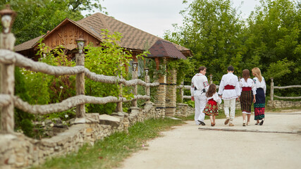 Beautiful couple with their children dressed in traditional costume walking together towards village