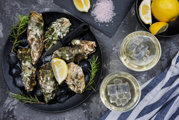 There are two glasses of white wine and freshly caught oysters on the table 