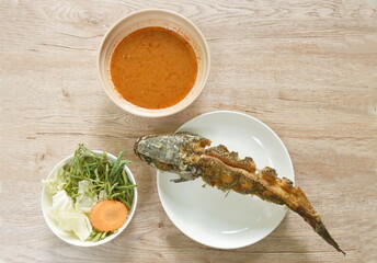 fried snake head fish and water mimosa with cabbage in spicy sour soup on plate