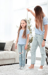 Young woman measuring her daughter's height at home