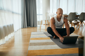 African American athletic man surfing the net on laptop at home.