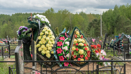 Artificial flowers and funeral wreaths on fresh graves in the city cemetery. City geaveyard.