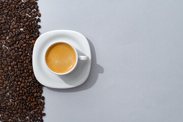 Cup of coffee with coffee beans on paper background. Top view
