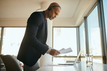 Young black entrepreneur prepares business reports for online meeting while working in office.