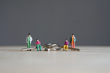 Miniature figurine character: two people sitting on Yin and Yang puzzle, two people standing on wooden floor for playing game competition, selected focus