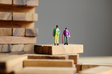 Miniature figurine character: two people standing on  pieces of wood of Jenga games 