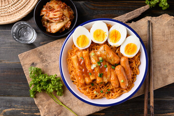 Korean spicy instant noodle with Tteokbokki, sausage and egg on wooden background, Table top view