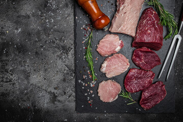 Different types of raw pork meat and beef on a dark background. various types of fresh meat pork...