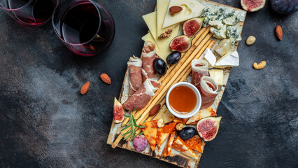 Appetizers table with italian antipasti snacks and wine in glasses. cheese, ham, nuts, fruit, bread sticks. Delicious balanced food concept. top view