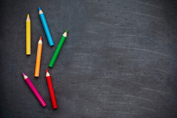 Colored pencils are laid out on a school black board, layout.