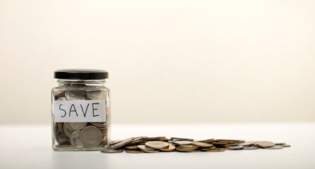 Coins in a glass jar and a pile of coins on the white table, Money Saving for the future concepts, business, investment, finance, copy space