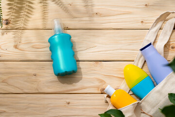 Sunscreen cream bottles in beach bag on wooden background