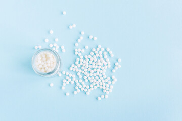 Homeopathic pills and a glass bottle on a blue background. Homeopathic medicine