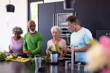 Poster Multiracial senior friends making fruits and leaf vegetables smoothie in kitchen at retirement home © WavebreakMediaMicro