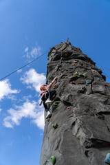 Kid in helmet having fun at bouldering wall. Little girl at outdoor climbing wall. Sports healthy lifestyle. Sport weekend action in adventure park.
