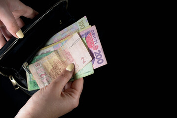 Ukrainian hryvnia various banknotes in hands from a black wallet on a black background