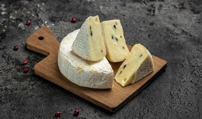 Brie cheese with a white and blue mold, camambert cheese. truffled brie cheese on a dark background, top view