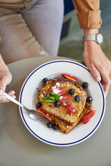 Comiendo tostadas francesas con frutos rojos. Delicioso brunch en restaurante