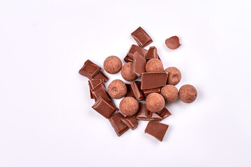 Top view pile of sweet brown chocolates isolated on white background. Delicious broken choco pieces.