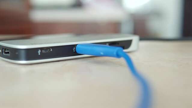 A human hand connects the USB cable to the hub close-up. 