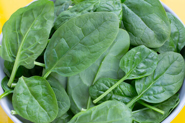 Fototapeta na wymiar Spinach leaves on yellow background.