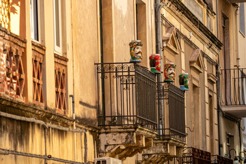 Fototapeta na wymiar Traditional Sicilian human ceramic Moorish heads on a decorated balcony of urban house in Taormina town, island Sicily, Italy, Europe, EU. Walking in old Mediterranean street in Italy