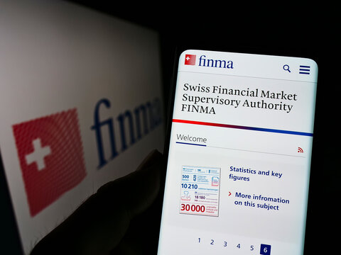 Stuttgart, Germany - 06-04-2022: Person holding cellphone with webpage of Eidgen&ouml;ssische Finanzmarktaufsicht (FINMA) on screen in front of logo. Focus on center of phone display.