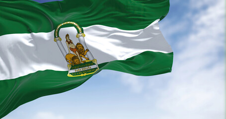 Andalusian flag waving in the wind on a clear day - obrazy, fototapety, plakaty