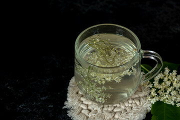 cup of tea from elder flowers on a black background.