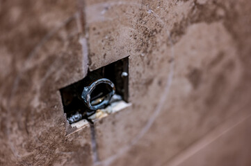 Cut-out section in bathroom shower tile with pipe connection protruding for water hookup. 