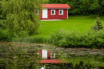 View on red holiday cabin with reflection in the pond water