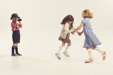 Portrait of three children, little boy taking photo of two cheerful girls holding hands and...