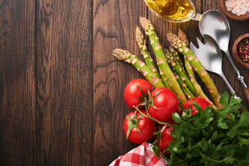 Parsley, parsley, tomato, garlic, olive oil, pepper, salt and salad fork and spoon on wooden cooking background. Food cooking background. Ingredients for cooking food background. Mock up. Top view.