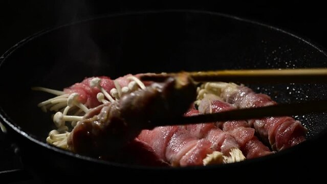 エノキの豚まきをフライパンで料理しているシーン