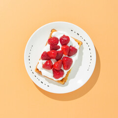 Fresh strawberries with Belgian waffle and whipped cream on white plate.