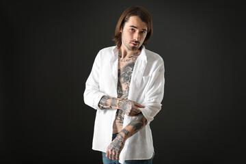 Young man with tattoos on body against black background