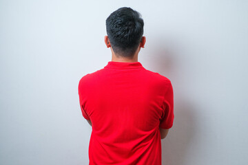 Young handsome Asian man wearing casual shirt and glasses standing back to camera with arms crossed