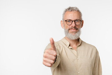 Happy european mature middle-aged man in beige shirt and glasses showing thumb up, good quality,...