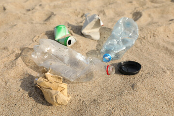 Fototapeta na wymiar Garbage scattered on sand, closeup. Recycling problem