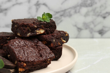 Delicious chocolate brownies with nuts and fresh mint on light grey table, closeup. Space for text