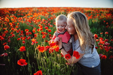 a little girl and her mom are happy with flowers and a sun in a poppy field